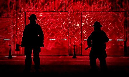 Firefighters silhouetted against red background